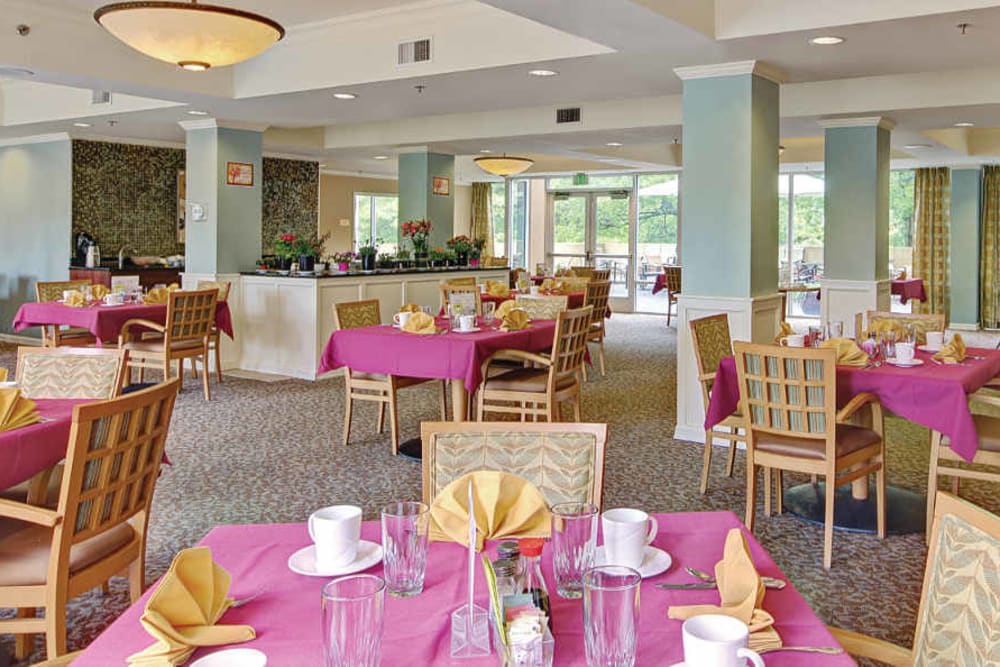 A beautifully set dining area with tables covered in pink tablecloths, ready for guests.