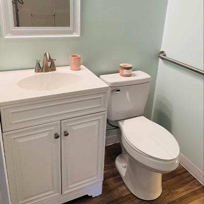A clean and compact bathroom featuring a white vanity, sink, mirror, and a toilet.