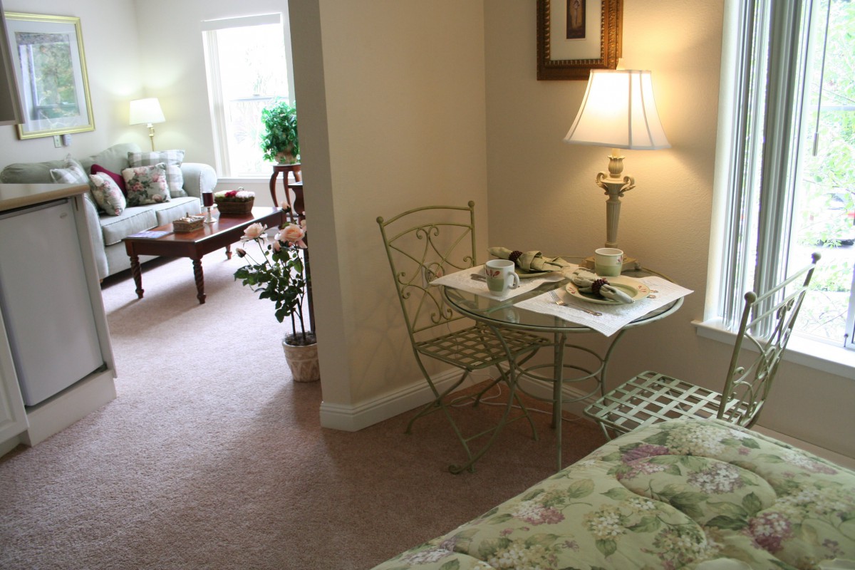A cozy interior with a small dining setup and a living area in the background.