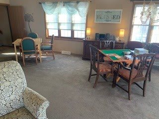 Cozy living and dining area with carpeted flooring and a mix of furniture.