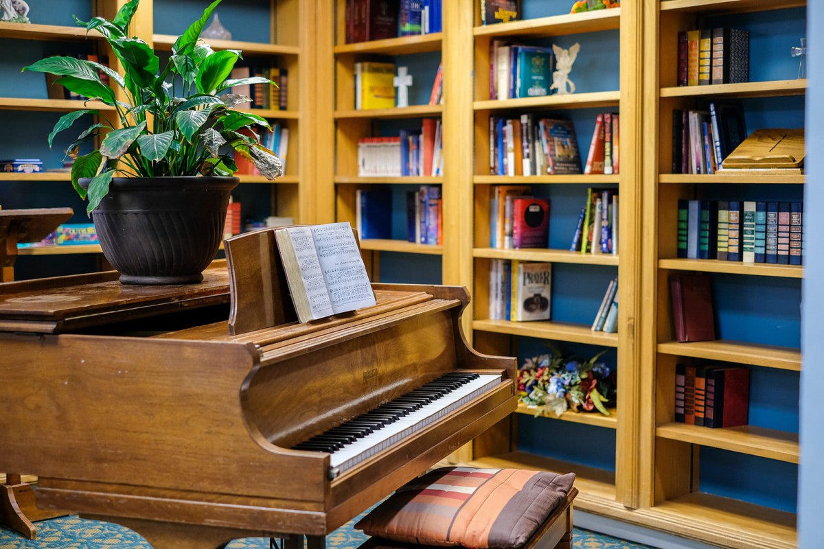 A cozy library corner featuring a piano and bookshelves filled with colorful books.