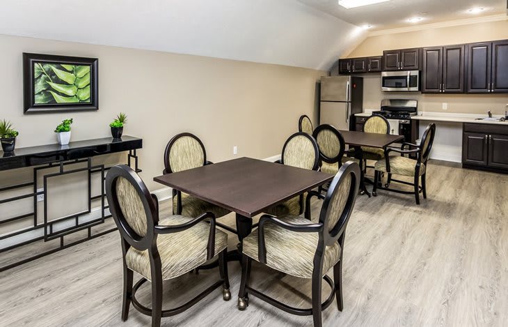 Modern kitchen with dining area featuring a dark wooden table and upholstered chairs.