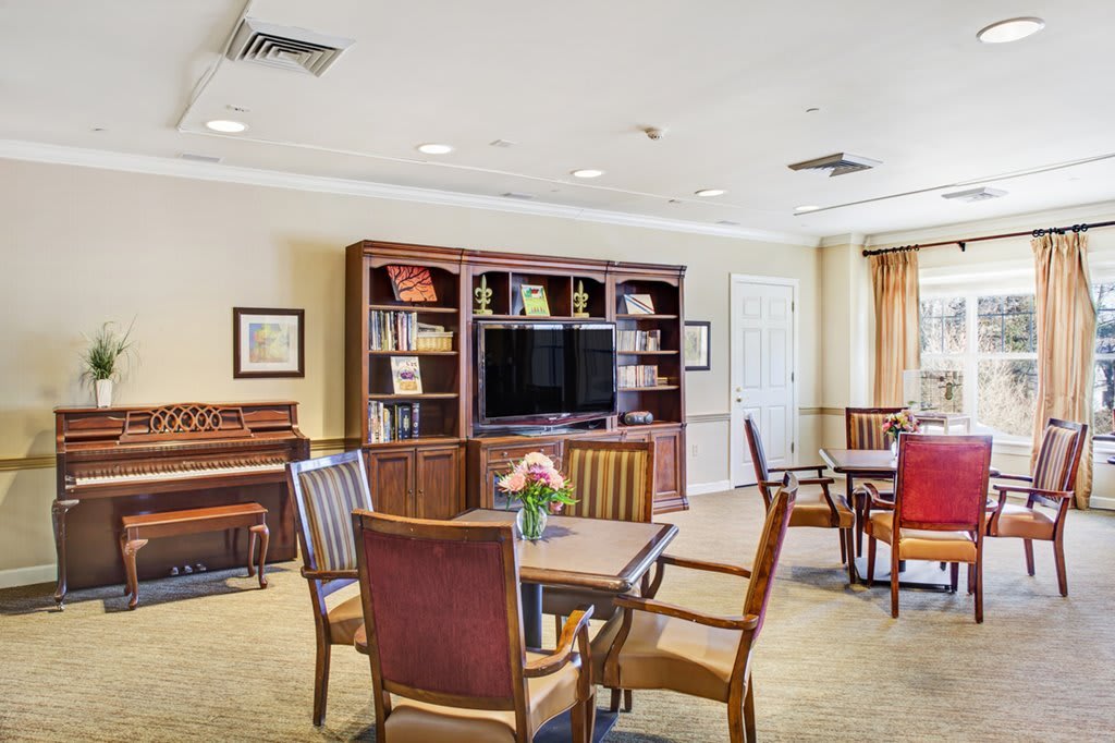 A cozy living room with a TV, piano, bookshelves, and seating area.