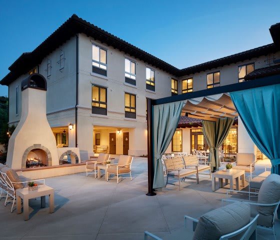 A serene hotel courtyard with comfortable outdoor seating and a cozy fireplace, perfect for evening relaxation.