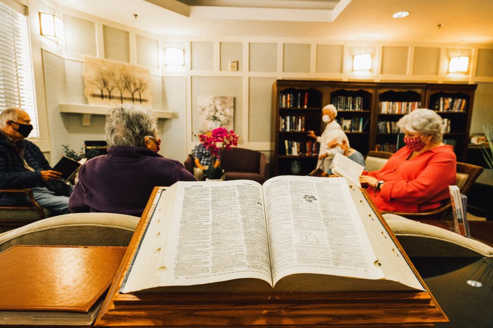 A cozy library setting where seniors gather for a reading session.