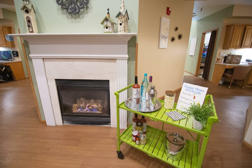 A cozy living space featuring a modern fireplace and a vibrant green cart adorned with decorative items.