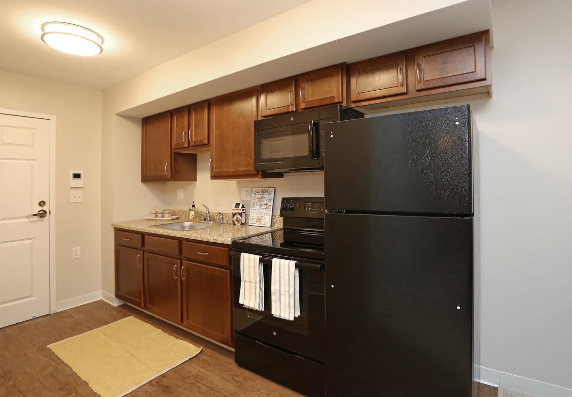 A cozy kitchen with wooden cabinets and black appliances.