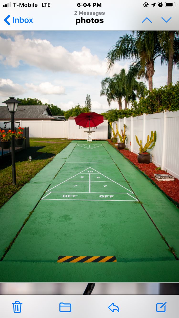 Outdoor shuffleboard court in a backyard setting.