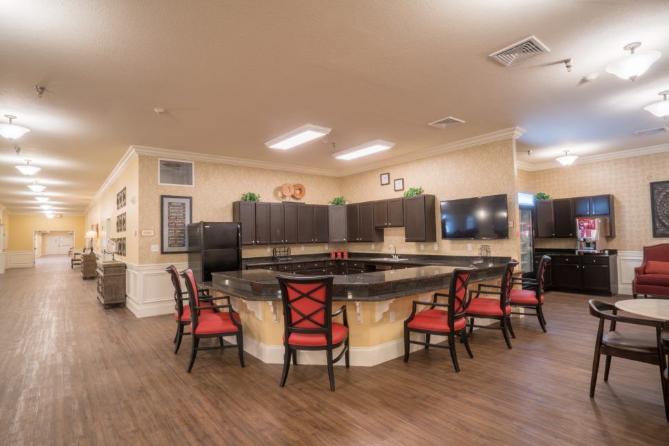 A modern kitchen with a central countertop surrounded by red-cushioned chairs.