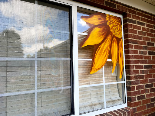 A beautifully painted sunflower accentuating the window of a home.