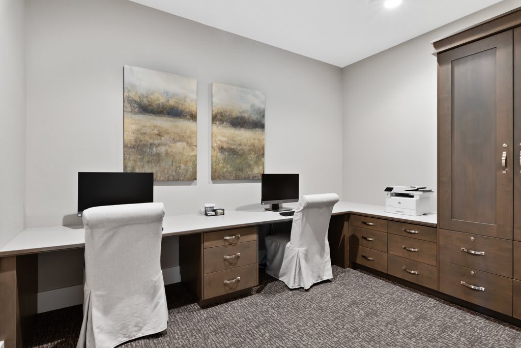 A modern office space with two workstations, featuring computer monitors and a printer.