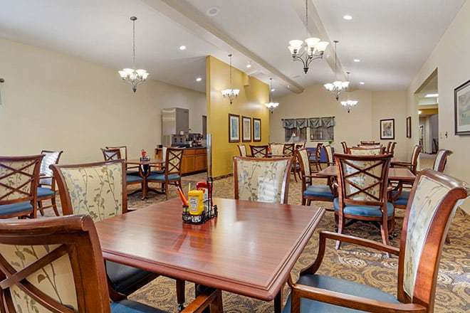 A spacious dining area with wooden tables and chairs, adorned with elegant chandeliers.