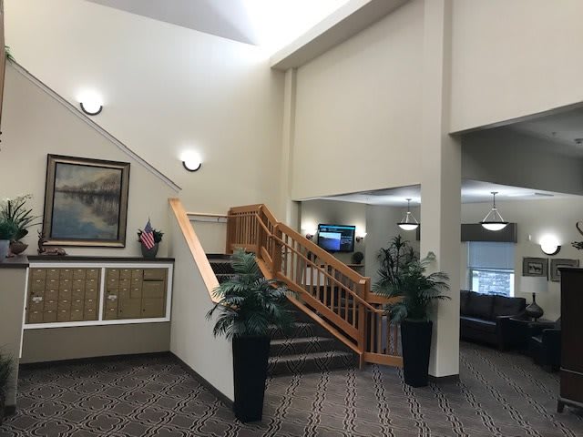 A spacious lobby with wooden stairs and decorative indoor plants.
