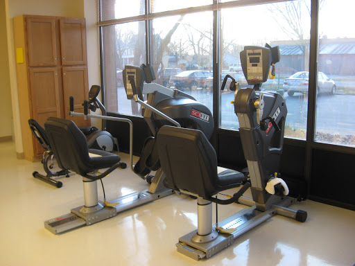A pair of recumbent exercise bikes positioned near a large window in a fitness setting.