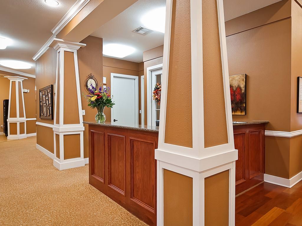 A warmly decorated office reception area with wooden paneling and decorative columns.