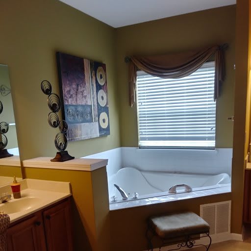 A bathroom featuring a corner bathtub with a window and wall art.