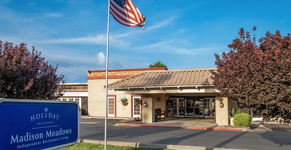 A hotel entrance with an American flag and clear signage.