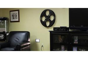 A living room decorated with a movie reel wall art above a cabinet.