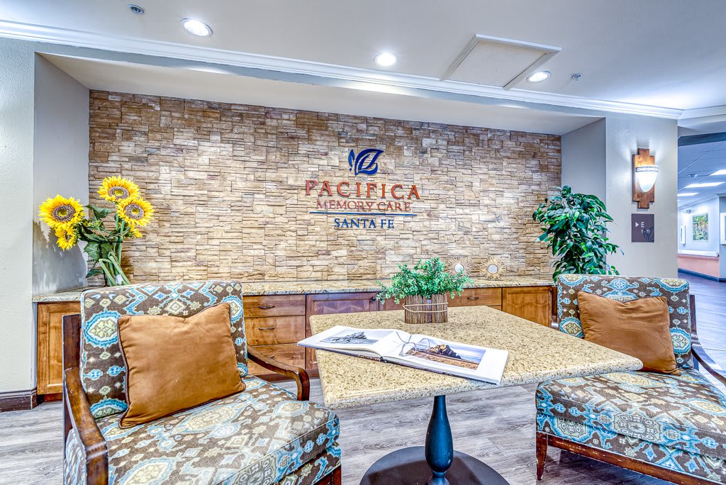 A cozy lobby area featuring comfortable seating and a brick accent wall with a business logo.