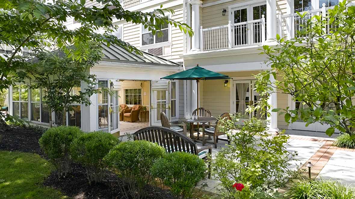 A tranquil garden patio with outdoor seating and an umbrella, set against the backdrop of a charming house.