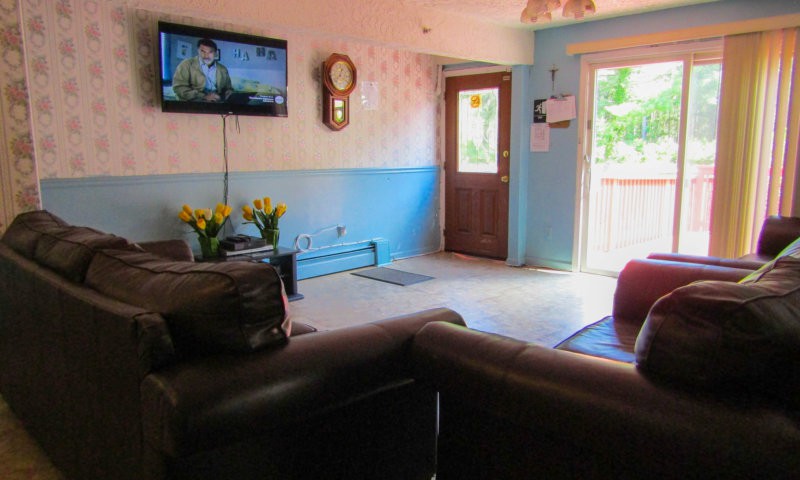 A cozy living room with a sofa, wall-mounted television, and door leading outside.