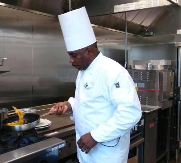 A professional chef prepares a dish in a commercial kitchen.
