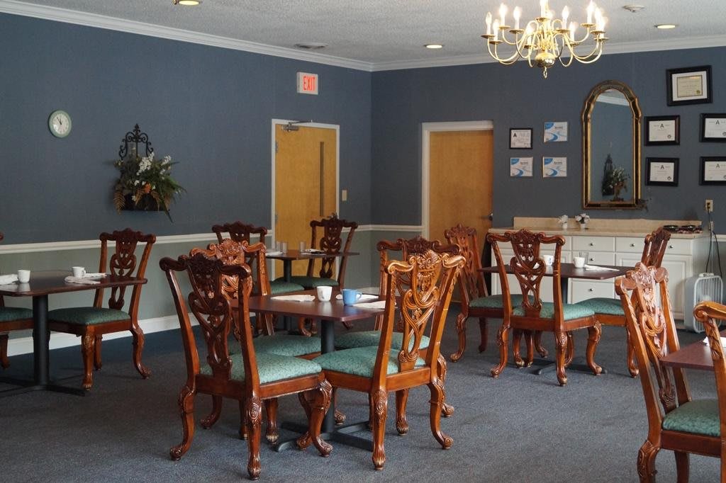 A well-furnished dining room with elegant wooden chairs and tables under a chandelier.