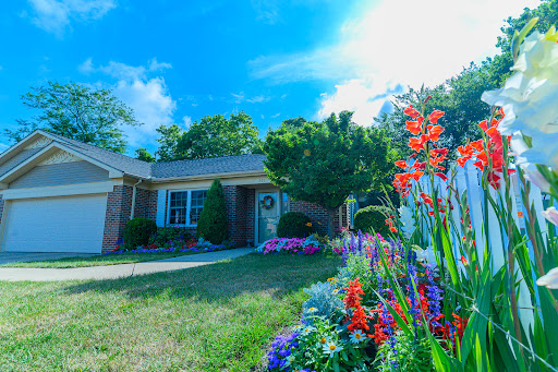 A charming home surrounded by vibrant flowers under a bright blue sky.