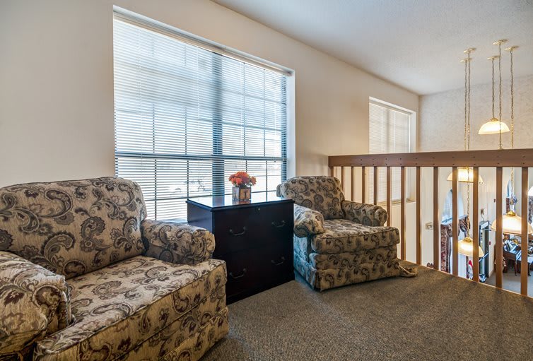 A cozy living space featuring two patterned armchairs near large windows with ample natural light.