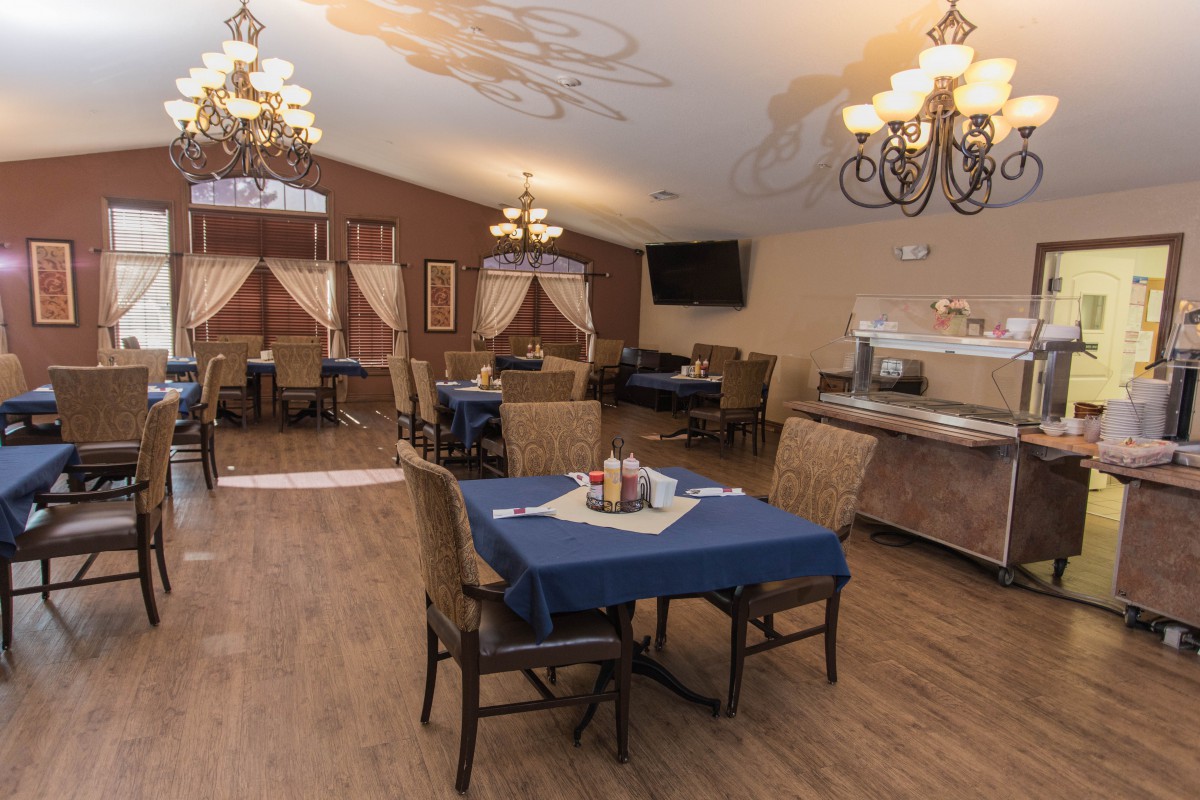 A cozy dining room with neatly arranged tables and elegant chandeliers.
