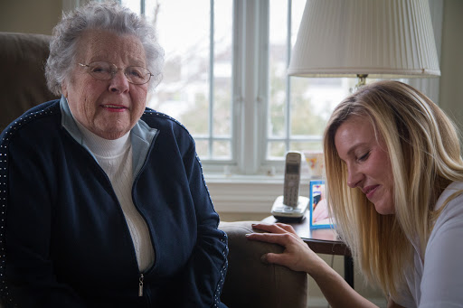 An elderly woman and a young woman share a moment indoors, highlighting the bond of caregiving and connection across generations.