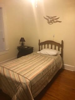A cozy bedroom with a single bed, nightstand and wall decor.