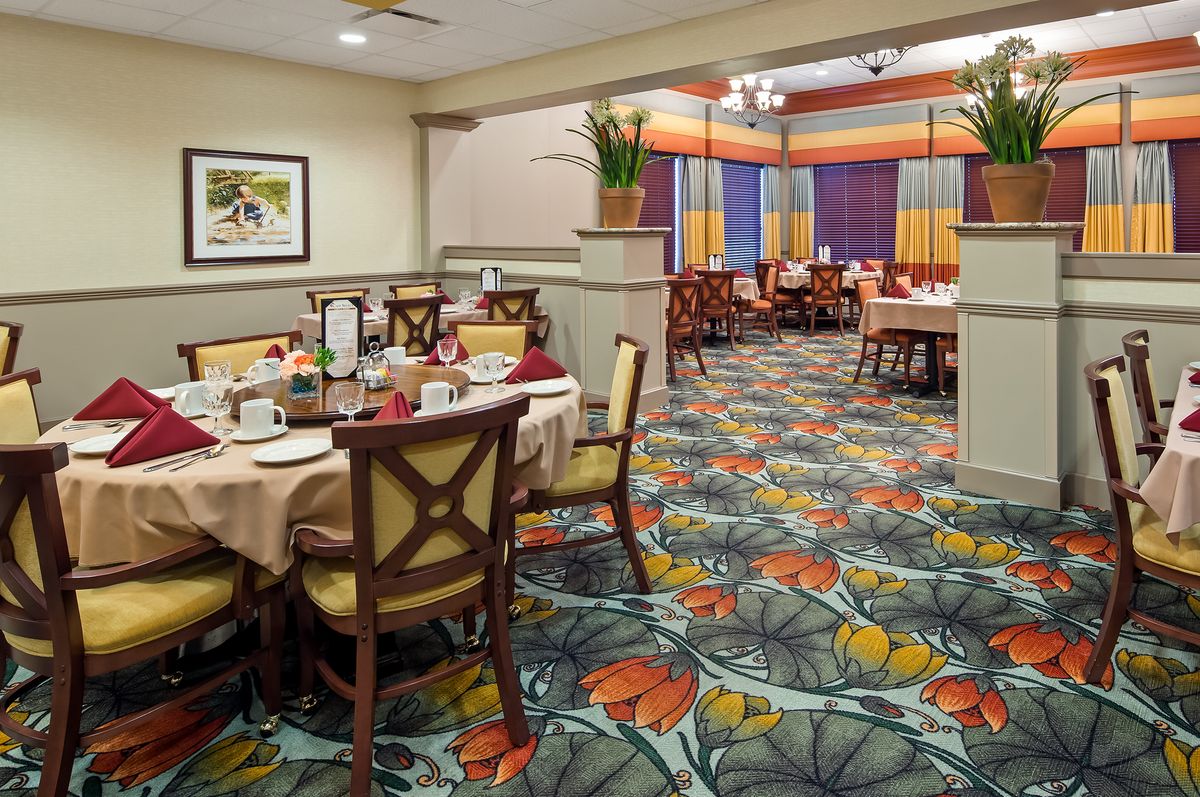 A cozy restaurant dining area featuring colorful carpet and elegantly set tables.