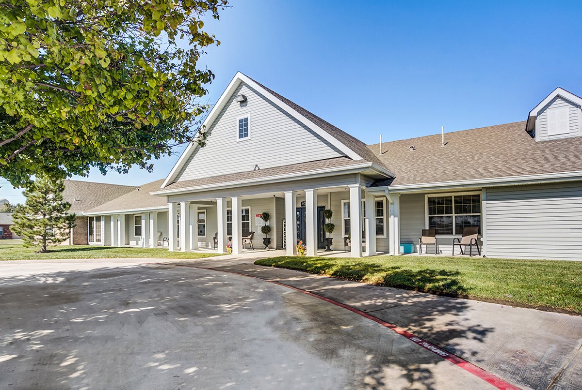 A large residential building with a welcoming entrance and landscaped front yard under a clear blue sky.