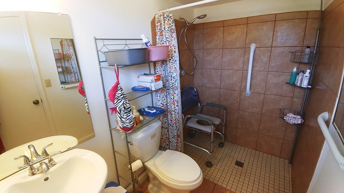 A bathroom with a shower, toilet, and storage shelves.