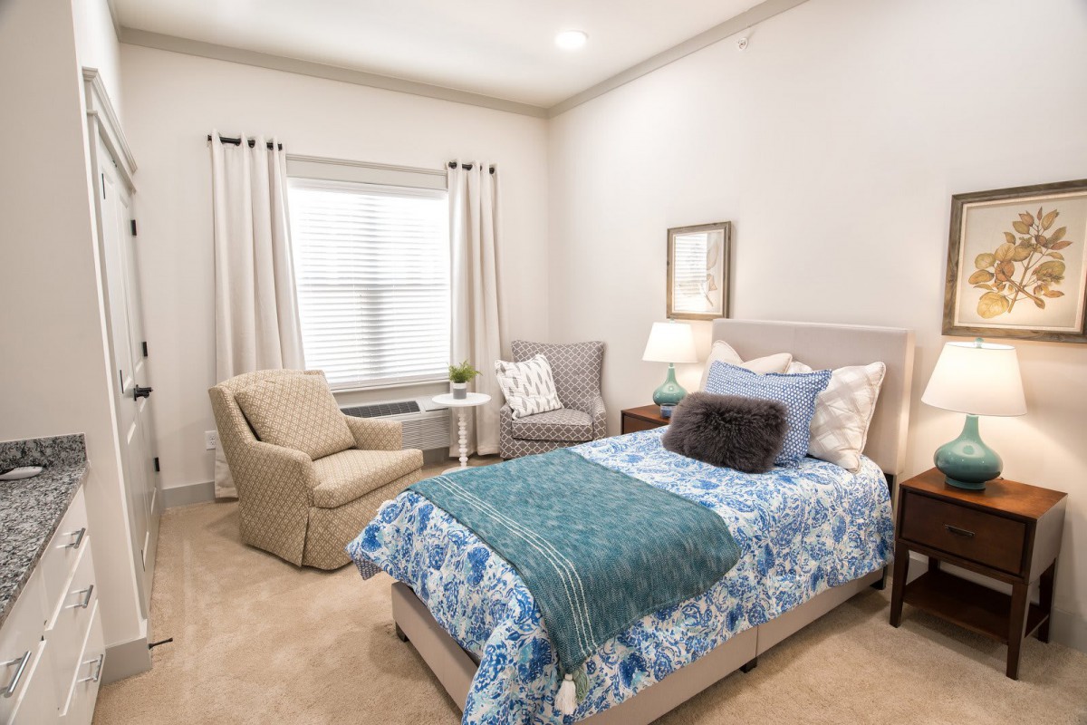 A cozy bedroom with a single bed, armchair, and elegant decor.