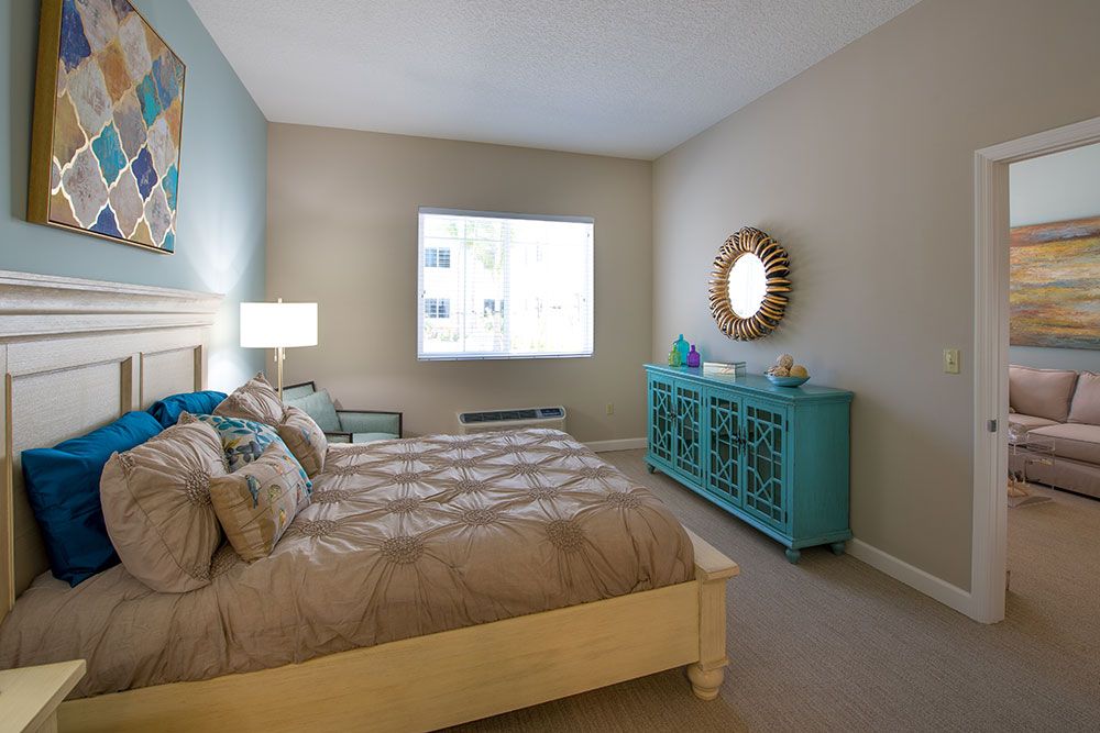 A cozy bedroom with a large bed, turquoise dresser, and decorative mirror.