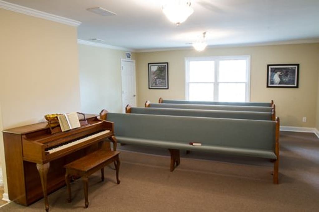 An interior room with a piano and several benches arranged in rows.