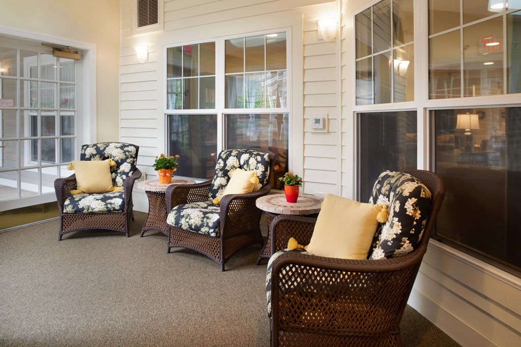 A cozy patio area with wicker chairs, floral cushions, and decorative plants.