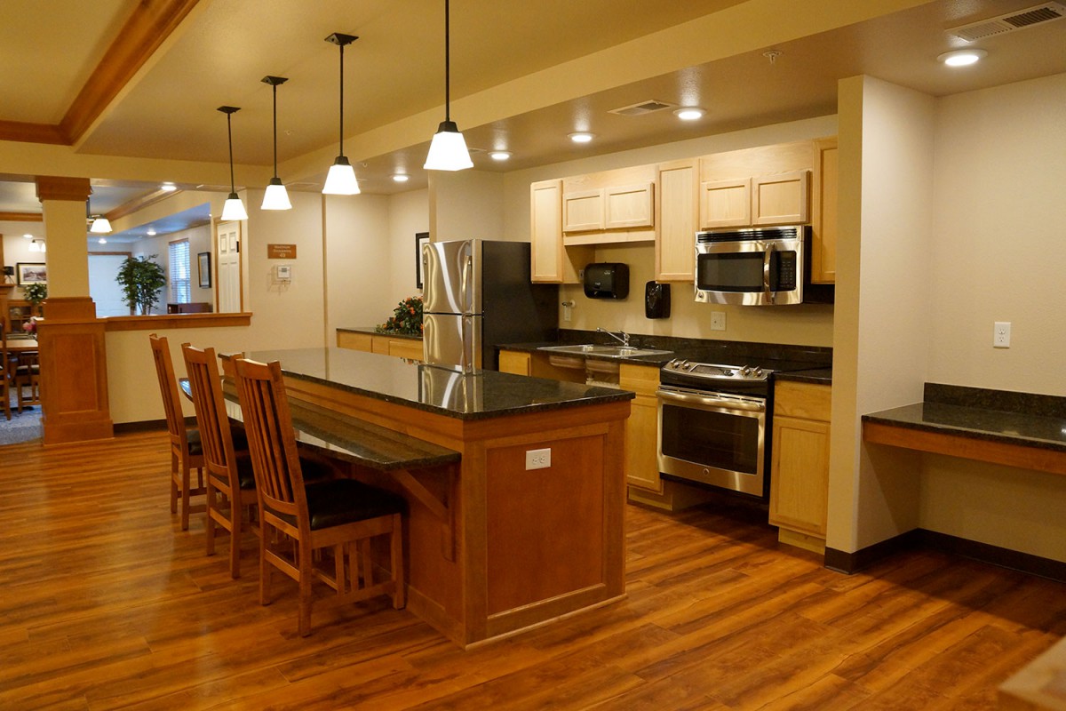 A modern kitchen with wooden floors, a spacious island, and stainless steel appliances.