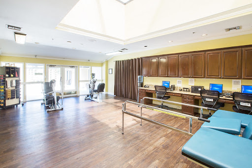 A spacious therapy room designed for rehabilitation, featuring exercise equipment and ample natural light.