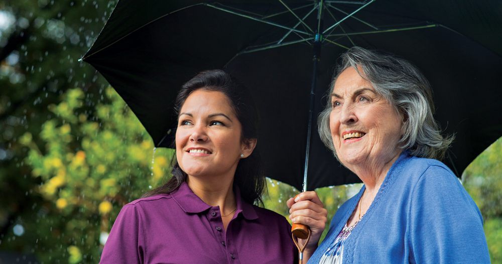 Two people smiling under an umbrella outdoors.