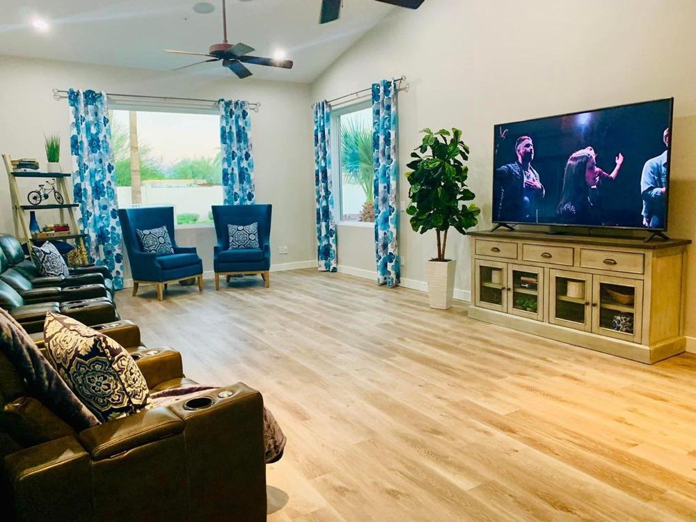 A spacious living room with modern decor, featuring a television, blue seating, and vibrant curtains.