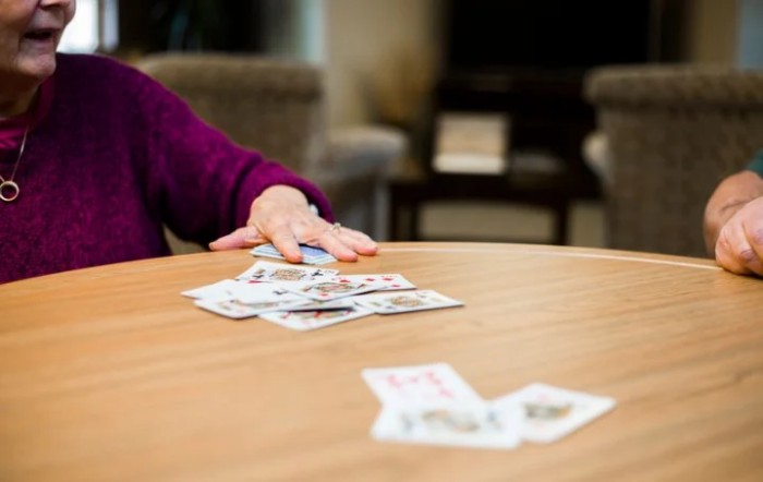 A person arranging playing cards on a table indoors.