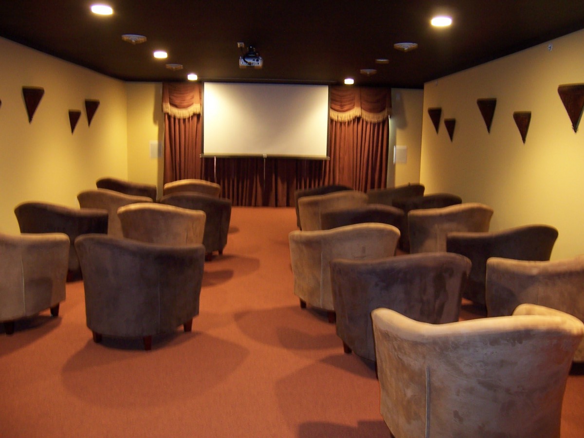 A cozy cinema room with arranged seating facing a large screen.