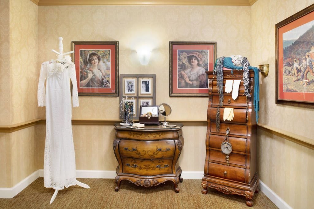 A vintage-themed room featuring antique furniture, artwork, and a dress form.