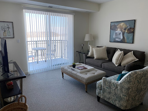 A cozy living room featuring a gray sofa, a stylish coffee table, and abundant natural light streaming through vertical blinds.