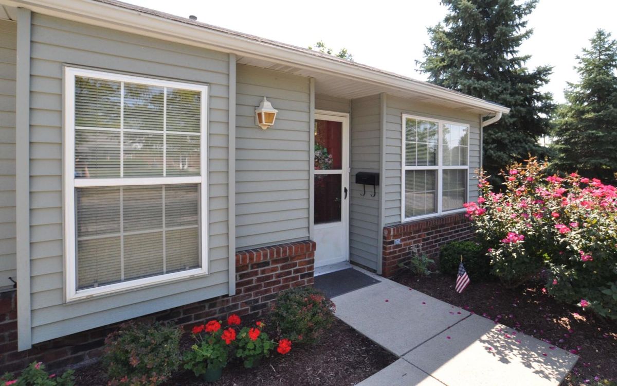 A cozy residential house with a front entrance, landscaped garden, and sidewalk.