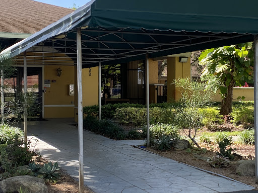 A covered walkway leading to an entrance, surrounded by well-maintained greenery.