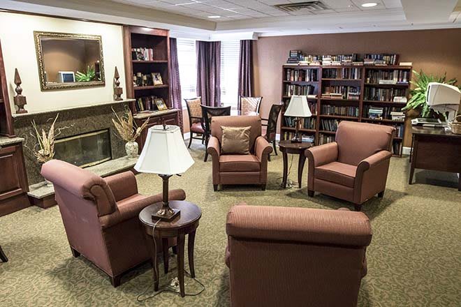 A cozy living room with comfortable chairs, bookshelves, and warm lighting.